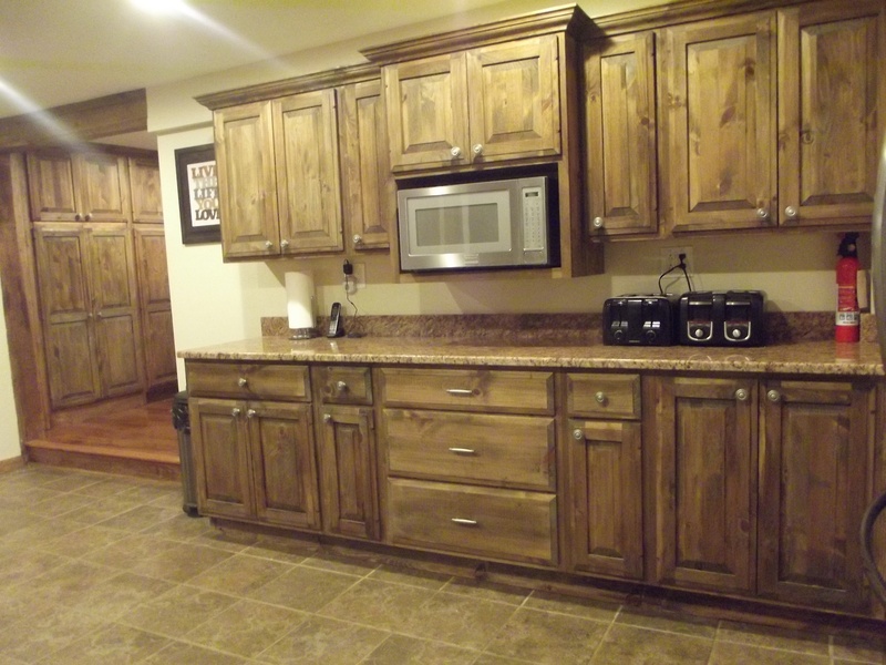A kitchen with brown cabinets and a microwave.