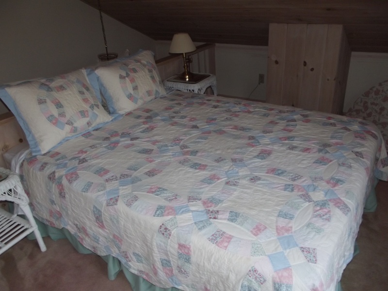 A bed with a blue and white quilt on it.