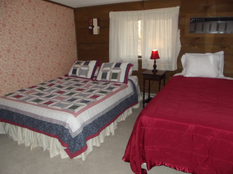 A bedroom with two beds and a red and white quilt.