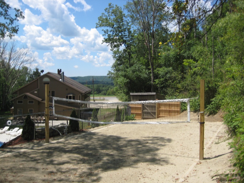 A sand volleyball court in a wooded area.