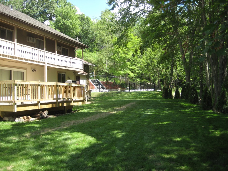 A house with a deck in the middle of a wooded area.