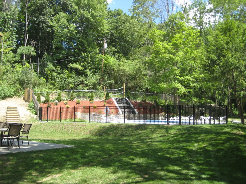 A backyard with a swimming pool and picnic tables.