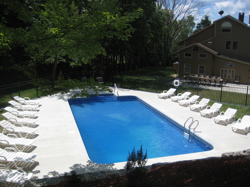 A swimming pool with lounge chairs and a deck.