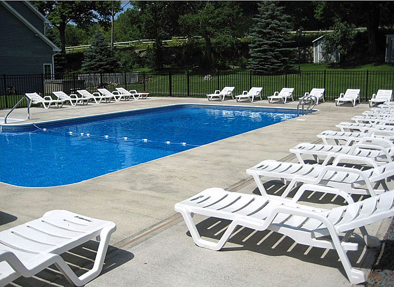 A swimming pool with white lounge chairs.