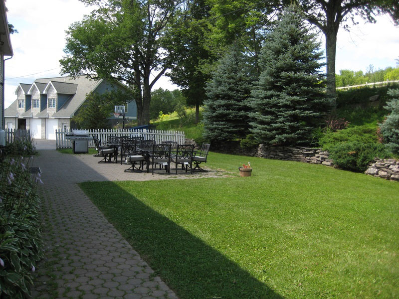 A lawn with tables and chairs in front of a house.