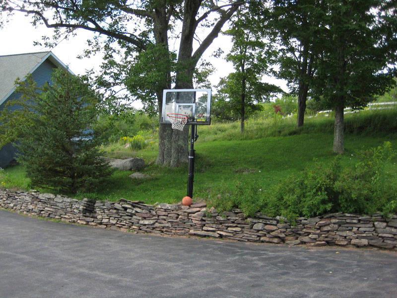 A driveway with a basketball hoop.