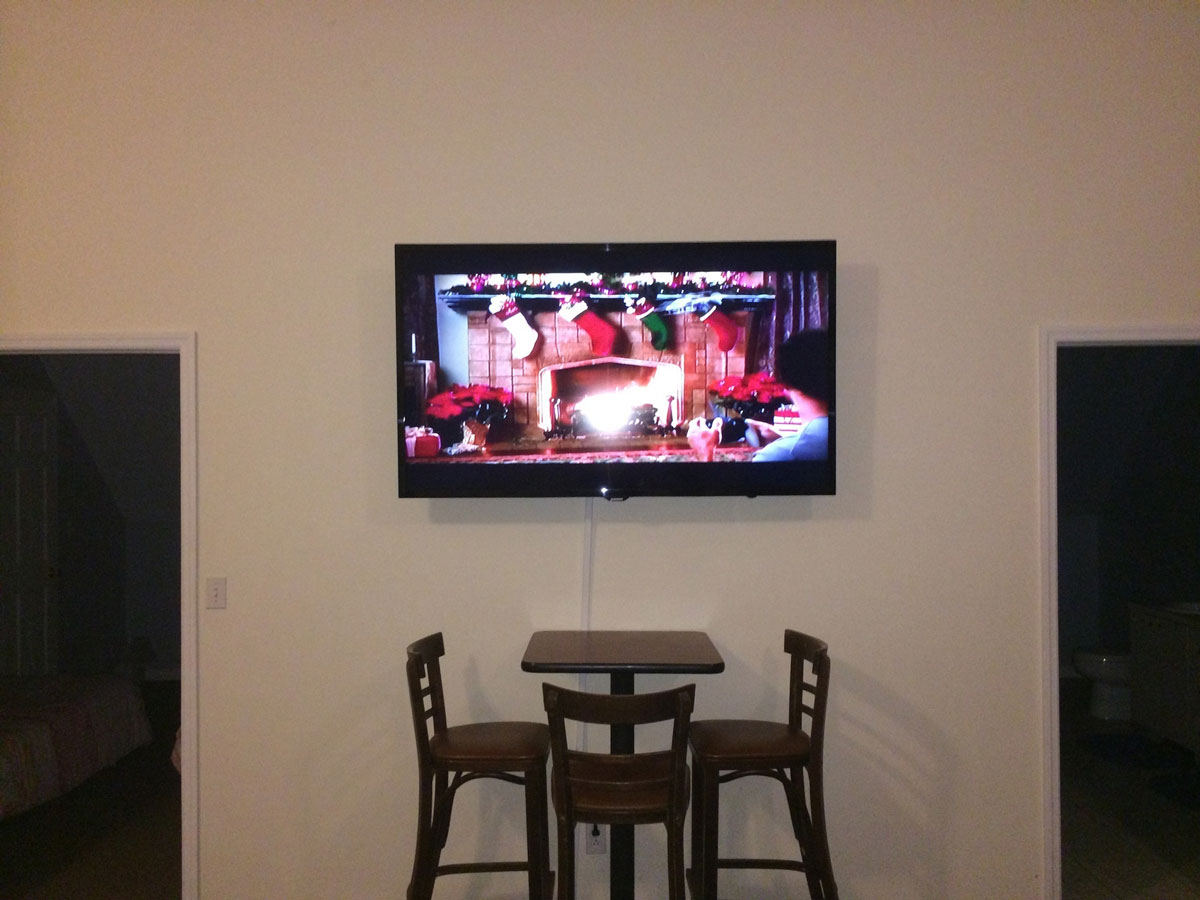 A tv mounted above a table and chairs.