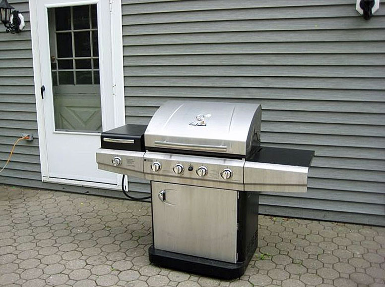 A stainless steel bbq grill in front of a house.