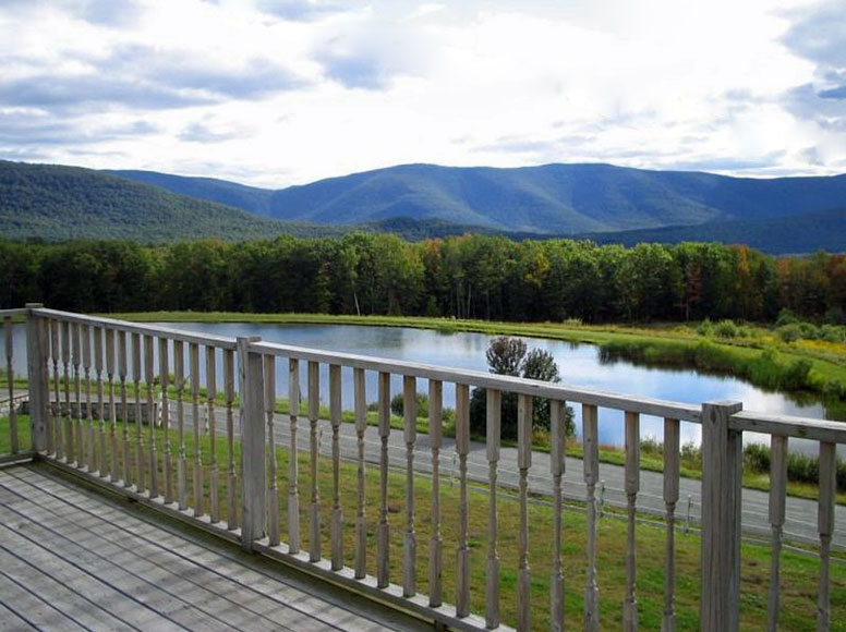 A deck overlooking a pond and mountains.