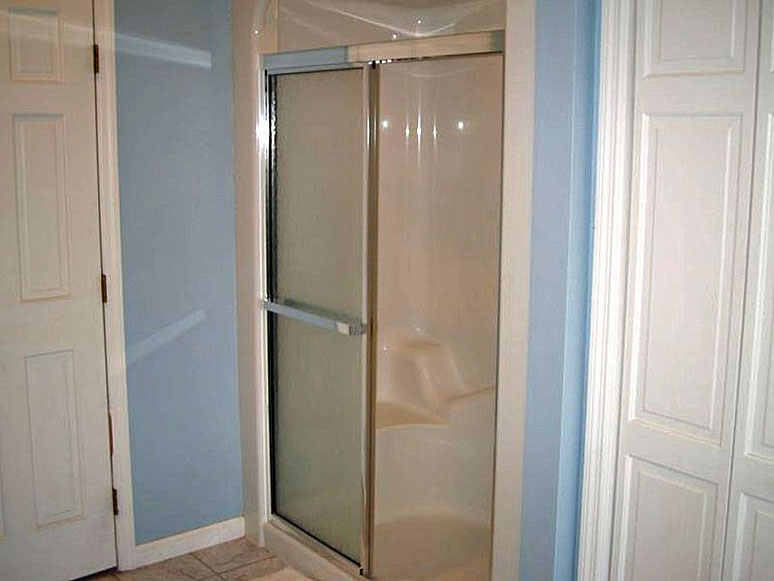 A white shower stall with a glass door.