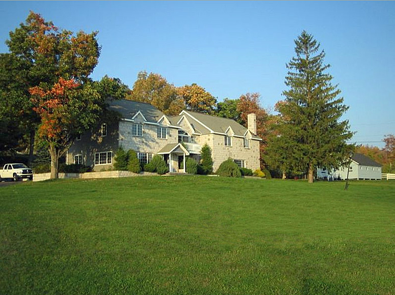 A large house in the middle of a grassy field.
