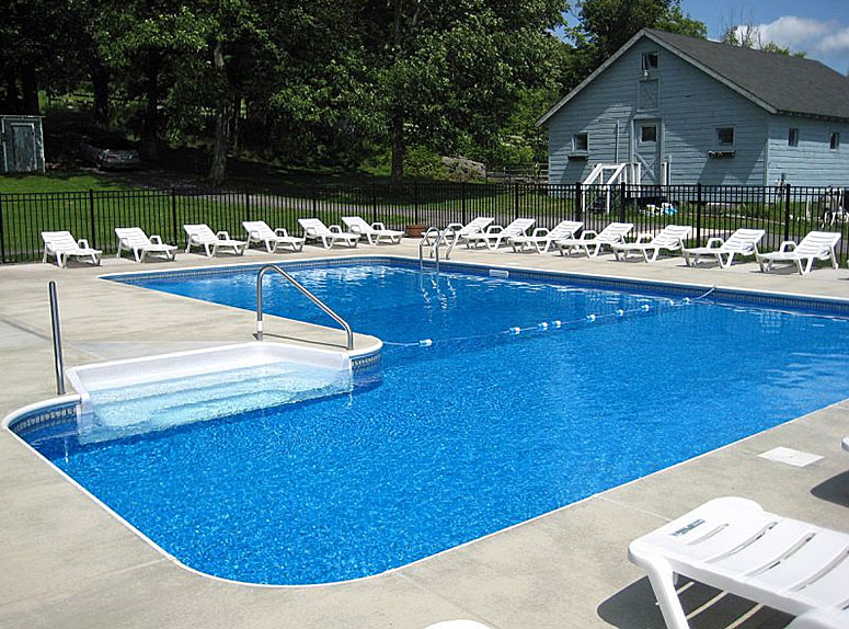 A swimming pool with lounge chairs and a deck.