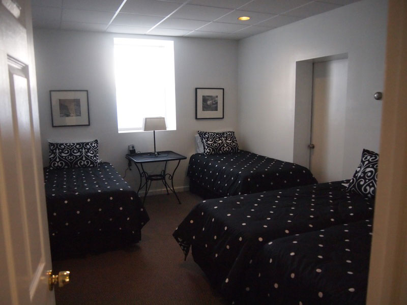 Three beds in a room with black and white polka dot covers.