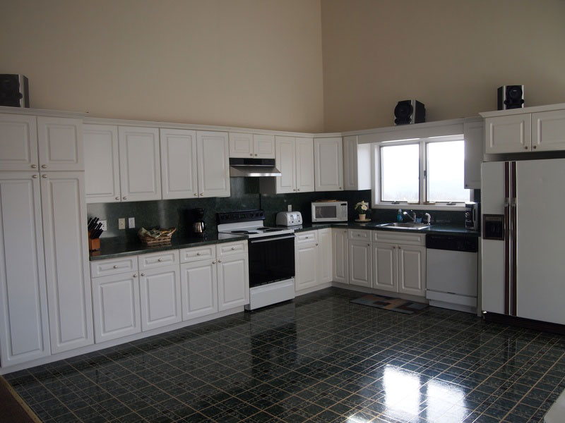 A kitchen with white cabinets and a green tile floor.