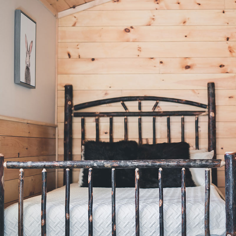 A bed in a log cabin with a black headboard.