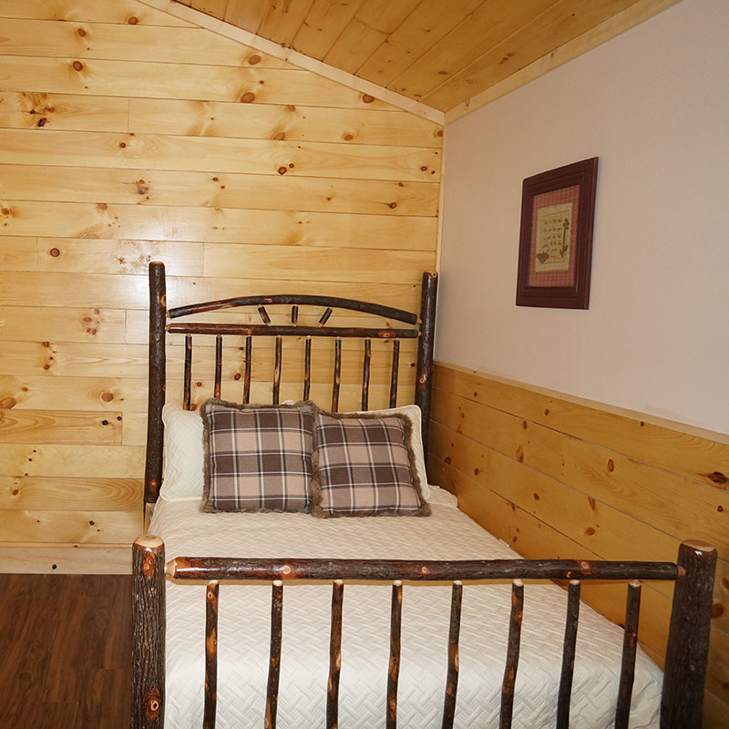 A bed in a room with wood walls.