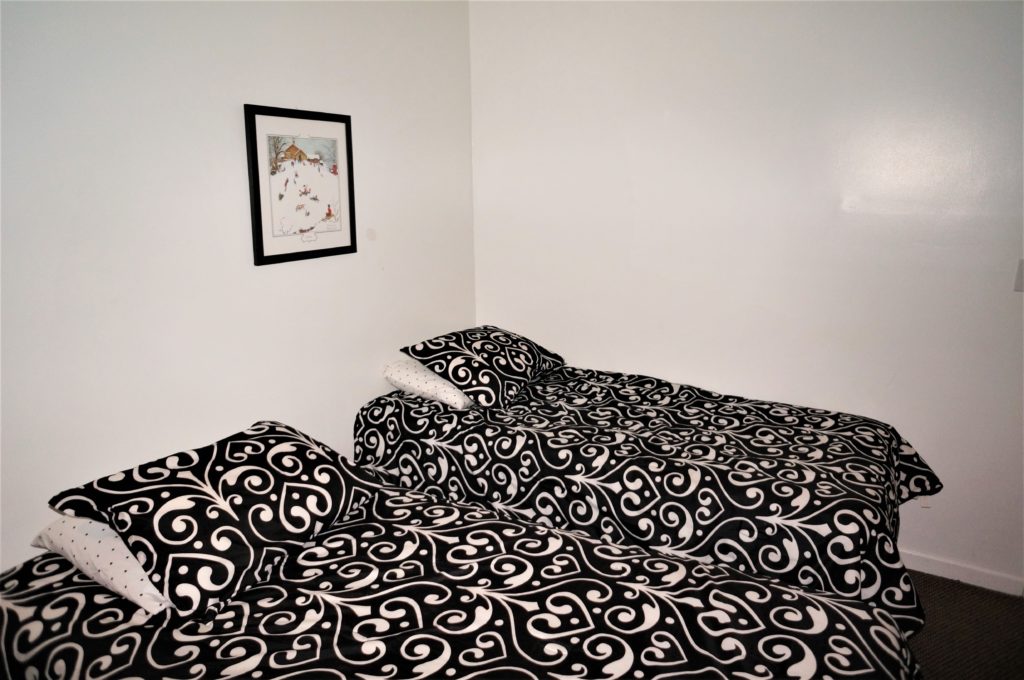 Two beds in a room with a black and white pattern.