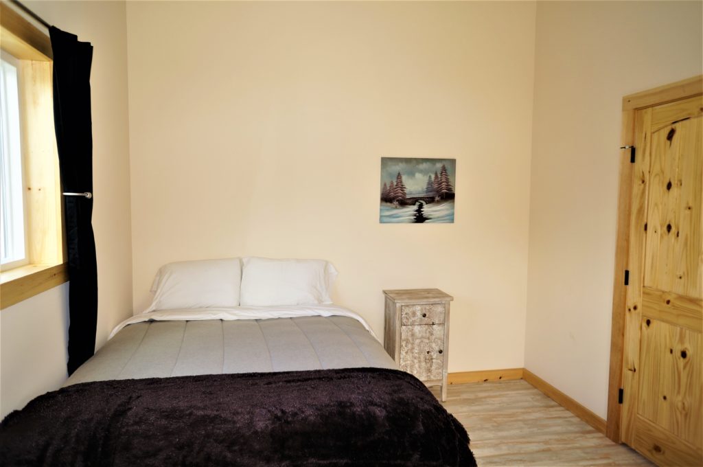 A small bedroom with a bed and a painting on the wall.