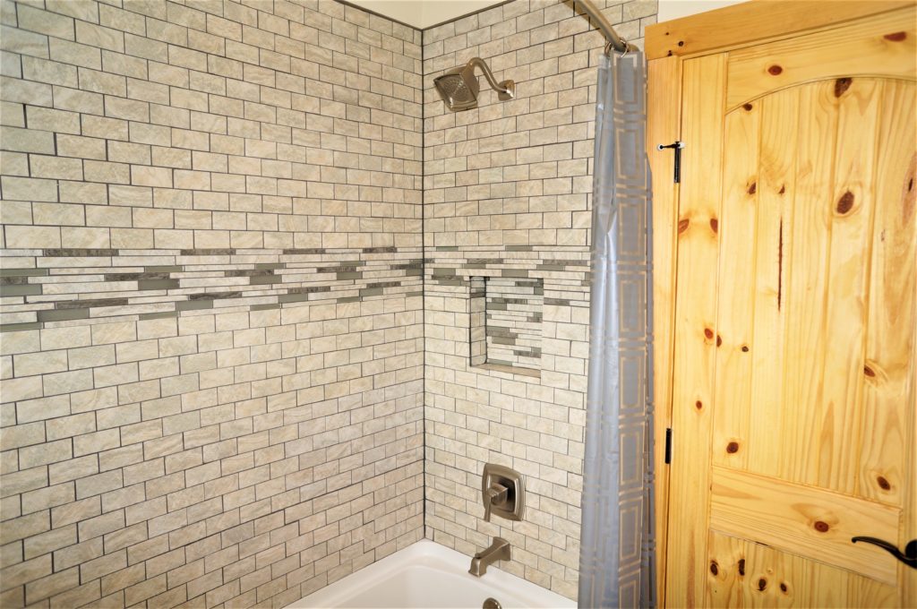 A tiled shower with a wooden door.