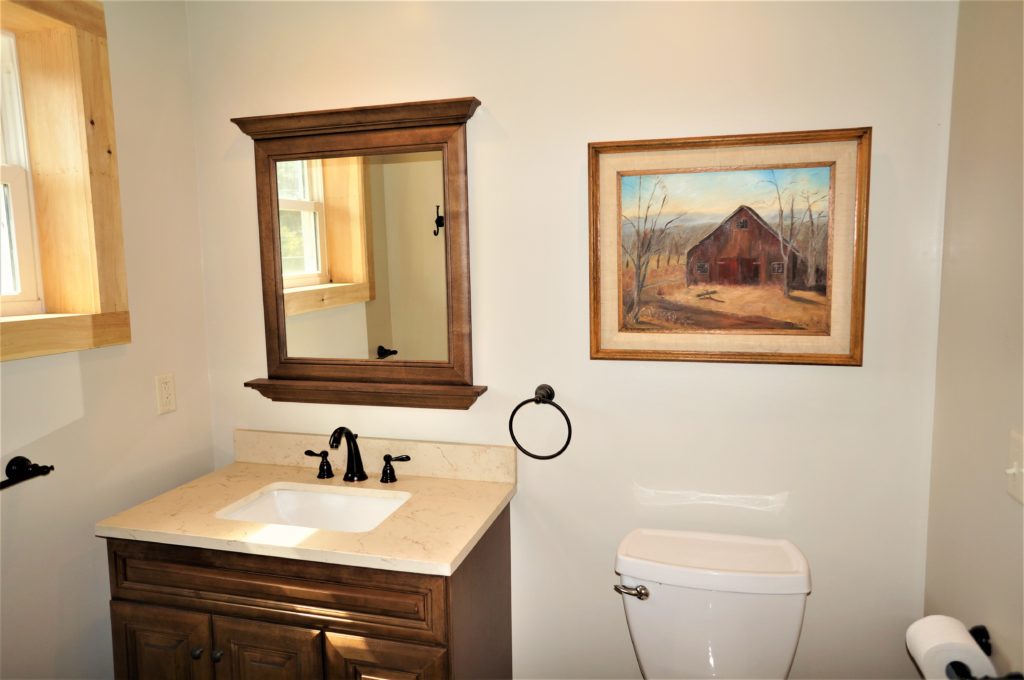 A bathroom with a toilet, sink, and mirror.