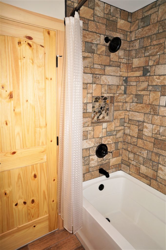 A bathroom with a wooden door and a stone wall.