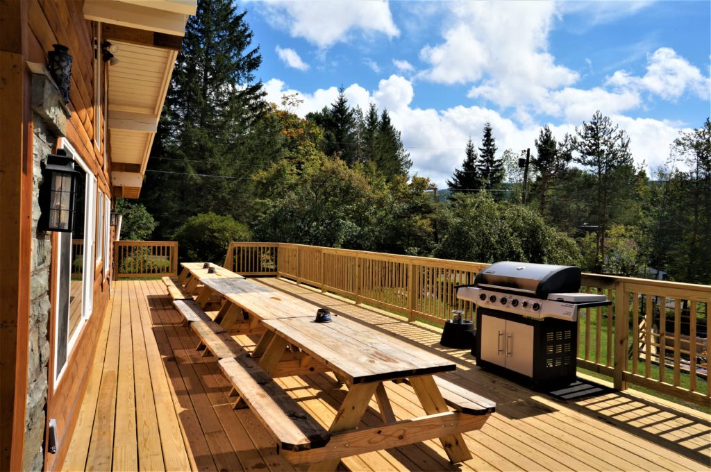 A deck with a grill and tables and benches