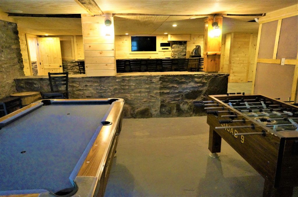 A pool table and foosball table in a basement.