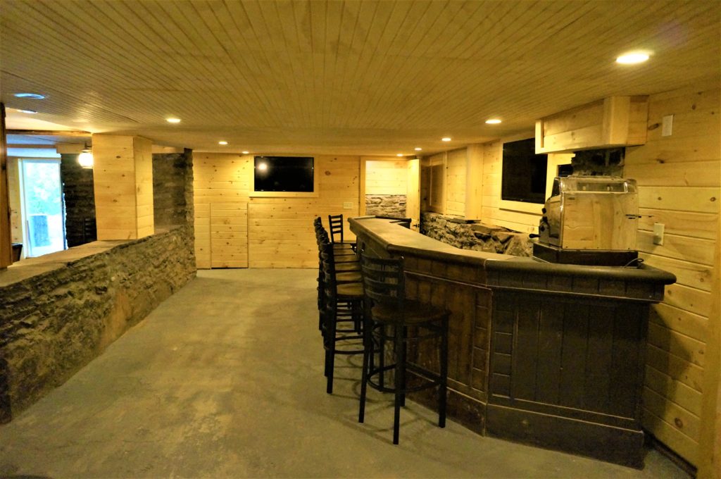 A basement bar with stools and a tv.
