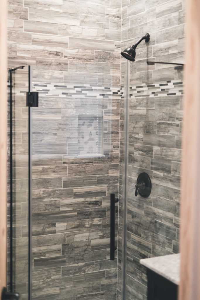 A bathroom with a glass shower stall and tiled walls.