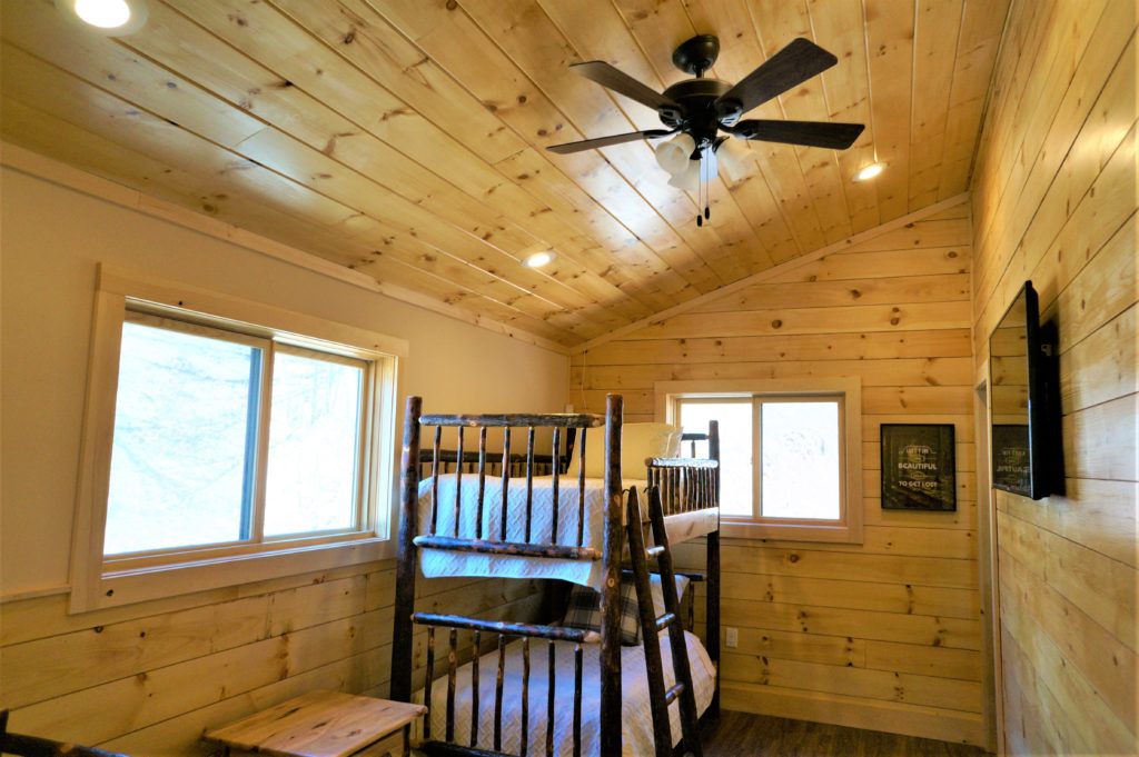 A room with a bunk bed and a ceiling fan.