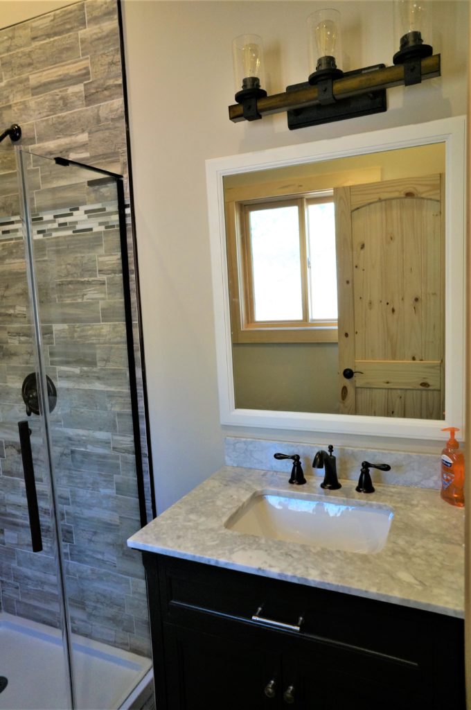 A bathroom with a sink, mirror and shower stall.
