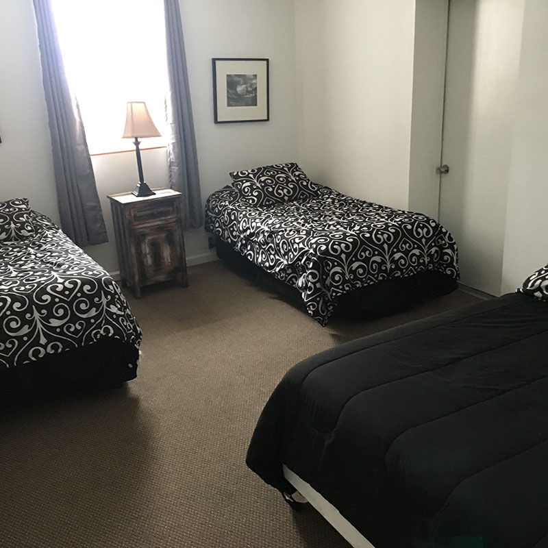Two beds in a room with black and white bedspreads.