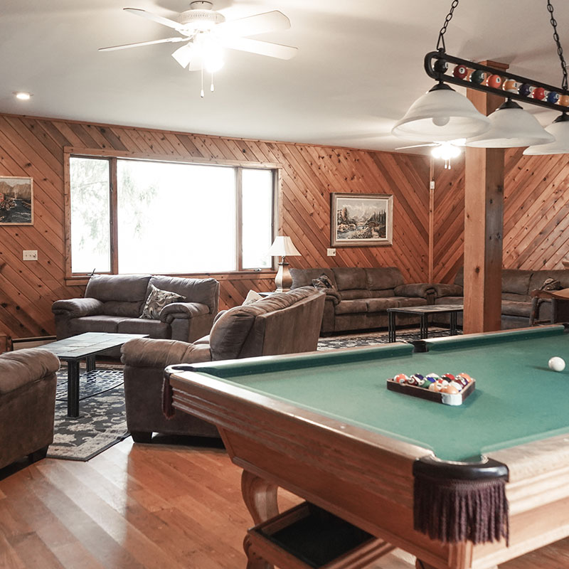 A living room with a pool table and couches.