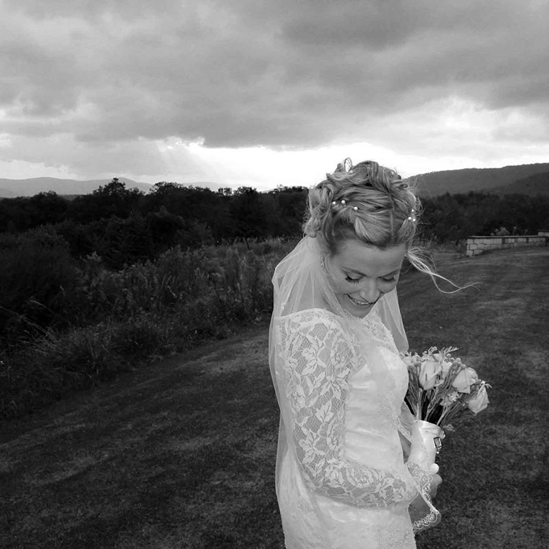 A black and white photo of a bride standing in a field.