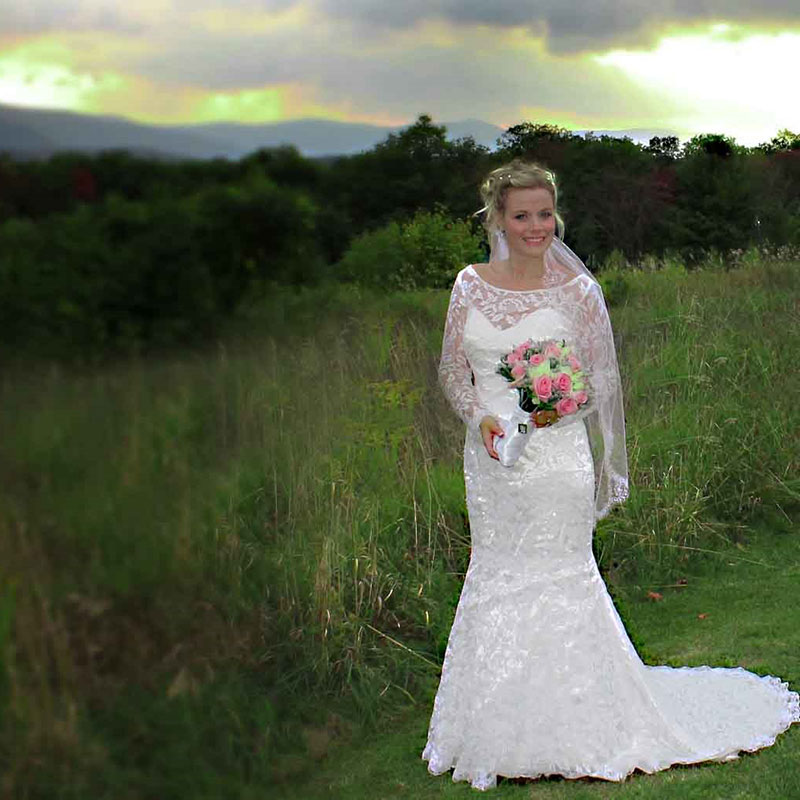 A woman in a wedding dress standing in a field.
