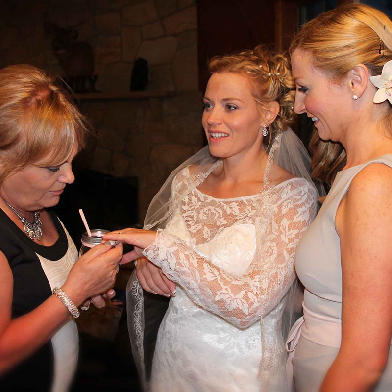 A woman is putting a ring on a bride's finger.