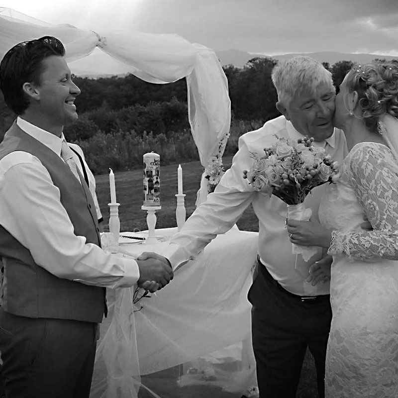 Black and white photo of a bride and groom kissing under a tent.