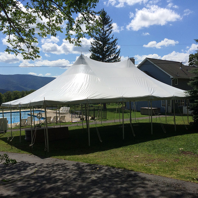 A large white tent is set up in front of a house.