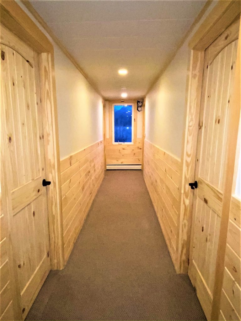 A hallway with wood paneling and a door.
