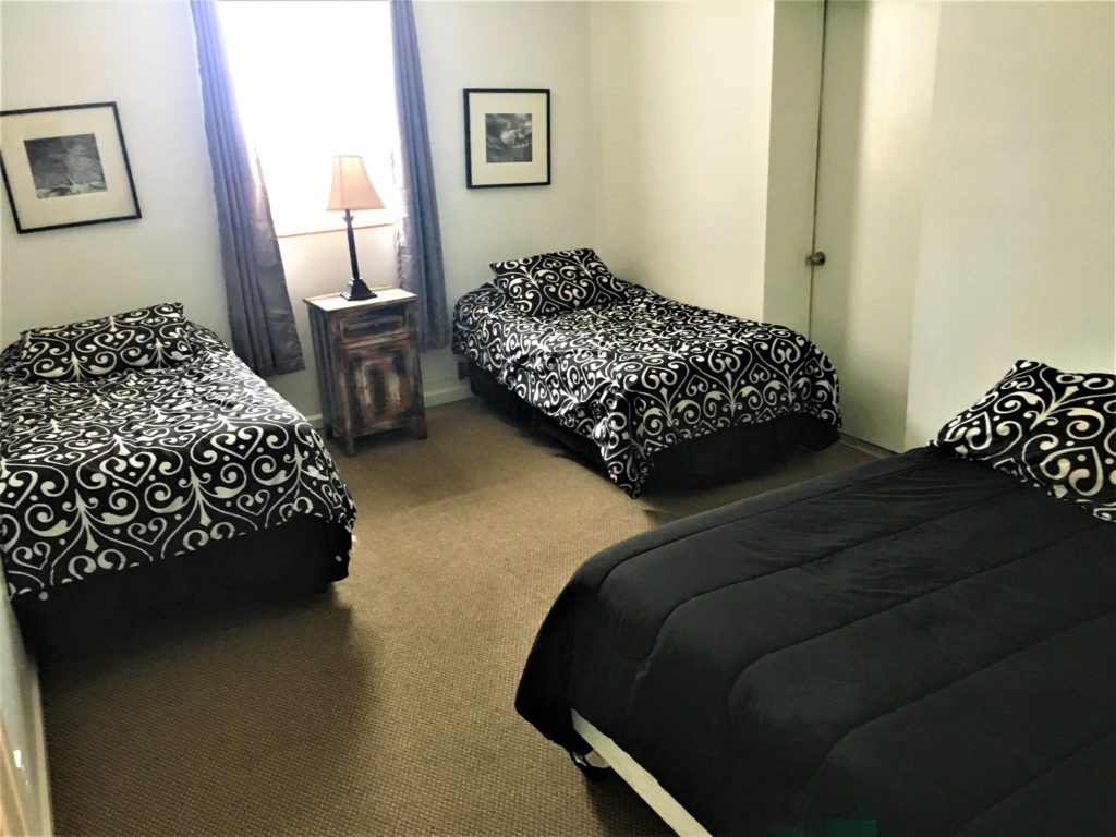 Two beds in a room with black and white bedspreads.