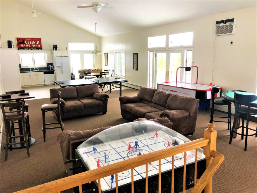 A living room with a pool table, foosball table, and air hockey table.