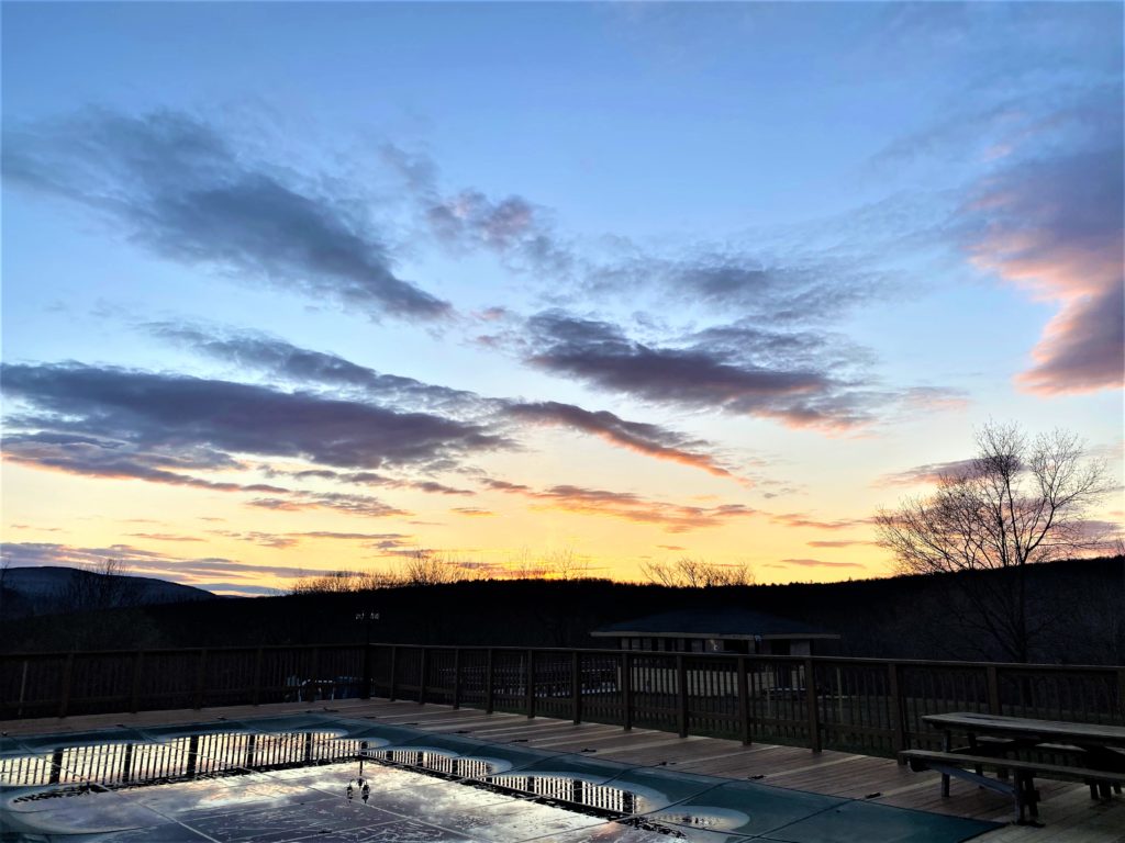 A pool with a view of the mountains at sunset.