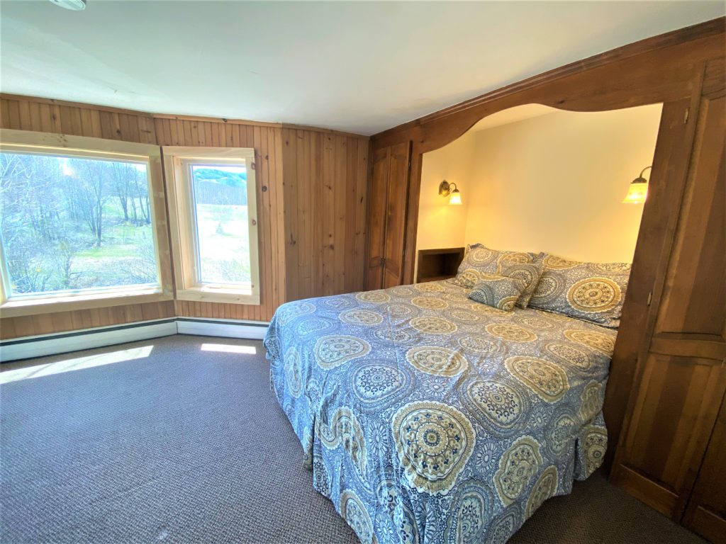 A bedroom with wood paneling and a bed.