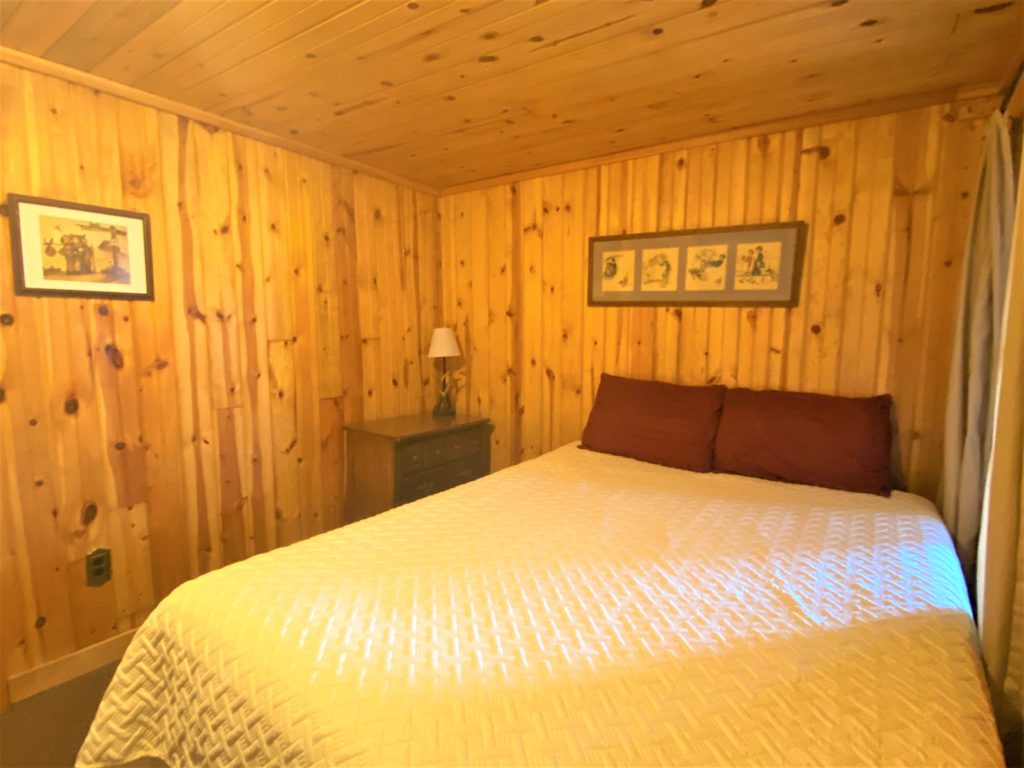 A bedroom with wood paneling and a bed.