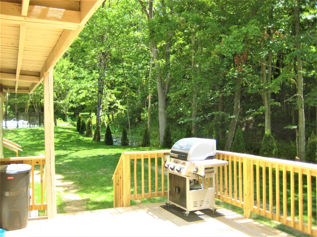 A wooden deck with a grill on it.