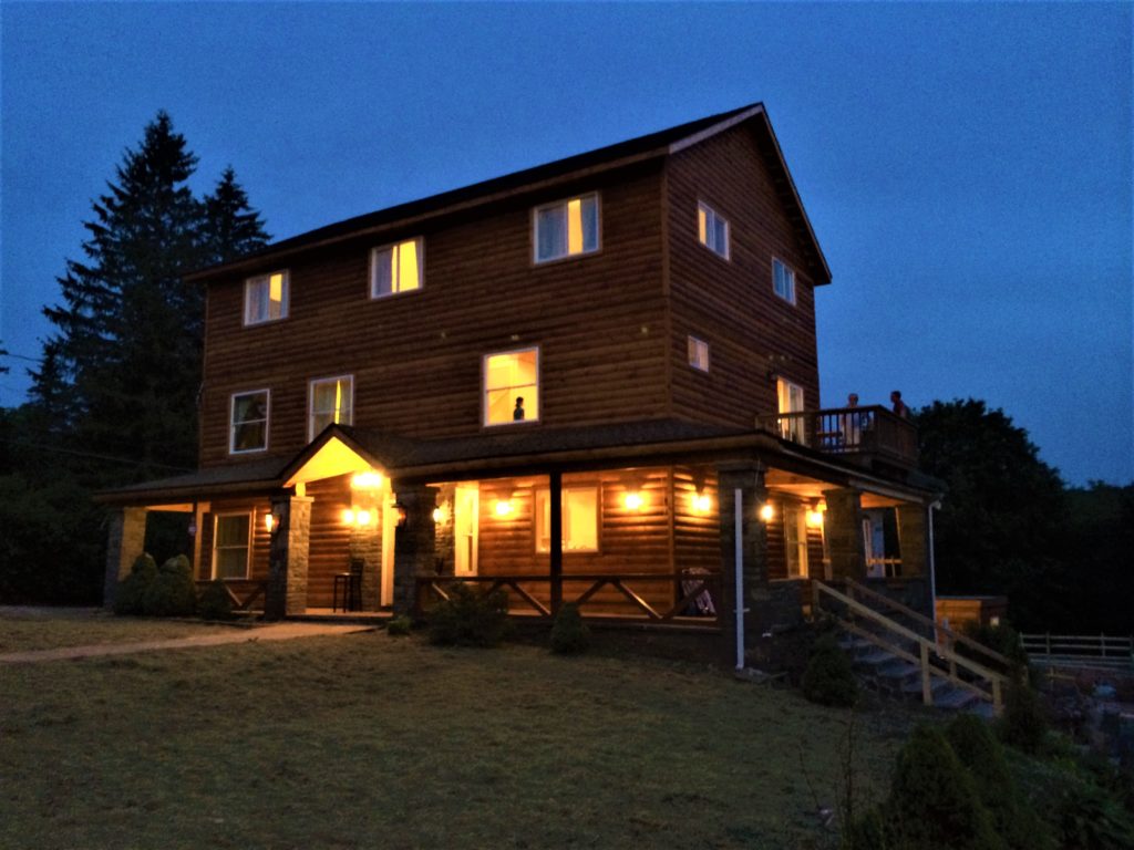 A wooden lodge with the lights turned on at night