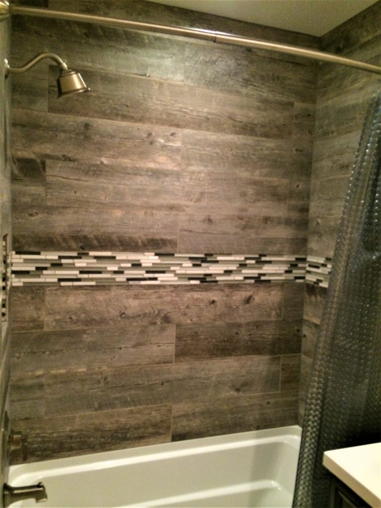 A bathroom with wood tile and a shower.