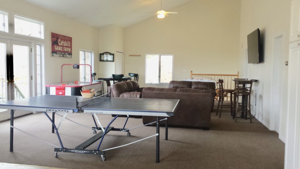 A living room with a ping pong table and couches.