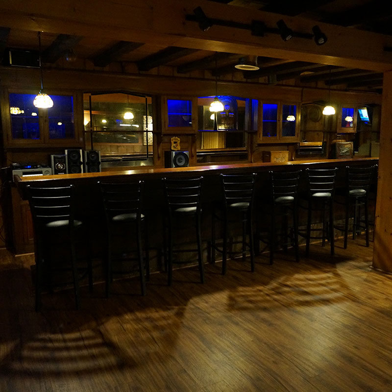 A bar with black stools and a wooden floor.