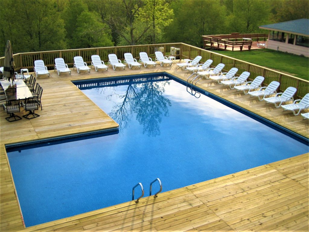 An l-shaped pool surrounded by pool lounge chairs